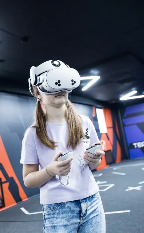 Подросток в VR-шлеме с контроллерами на арене VERTIGO